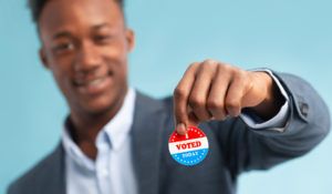 junger Mann, der den Aufkleber „I Voted“ hält