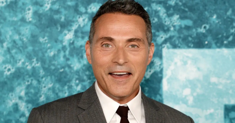 Rufus Sewell in abito grigio e cravatta nera sorride alla prima di'Old' at the Lincoln Center in 2021