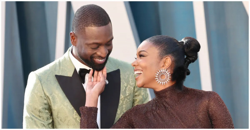(l-r): Dwyane'as Wade'as šypsosi žiūrėdamas į savo žmoną Gabrielle Union, dėvinčią suknelę su blizgučiais ir sidabrinius auskarus.