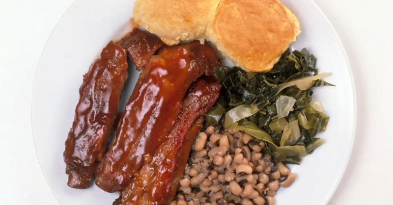 Isang stock na larawan ng isang plato ng ribs, cornbread, collard greens, at black eyed peas