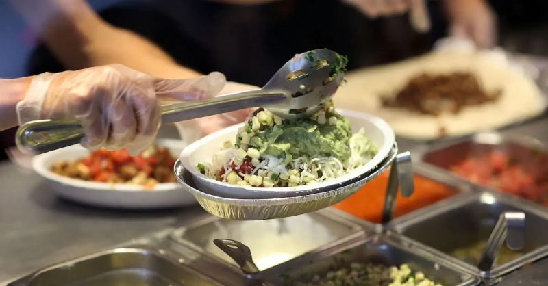 Работник Chipotle выполняет заказ чаши