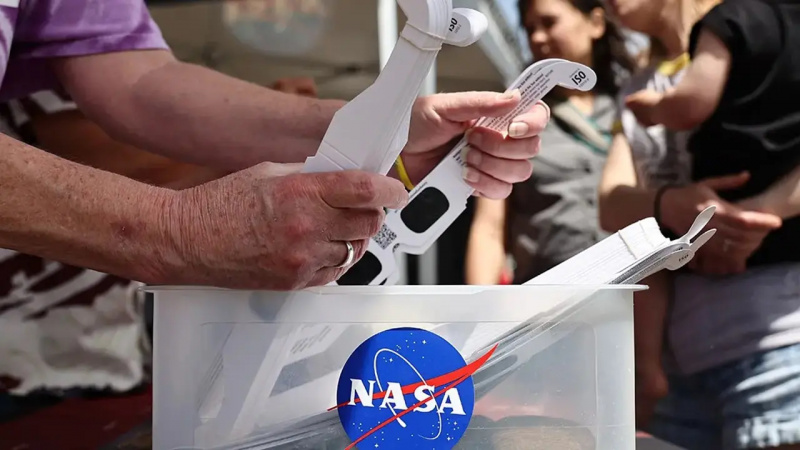 Una persona con in mano degli occhiali per l'eclissi solare della NASA