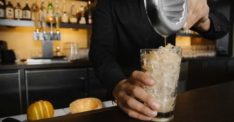 Barman turnând suc în shaker - fotografie stoc