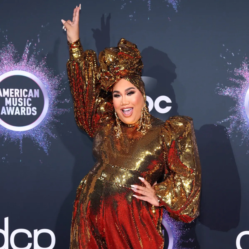 Patrick Starrr ma na sobie złoty kombinezon i trzyma znak pokoju podczas gali American Music Awards 2019 w Microsoft Theatre, 24 listopada 2019 r. w Los Angeles, Kalifornia.