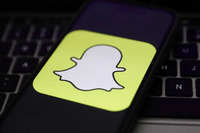 Snapchat-logotyp på telefonen på datorns tangentbord