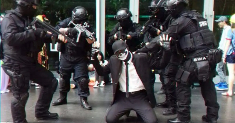 Shadmano cosplay ant kelių, apsuptas SWAT komandos