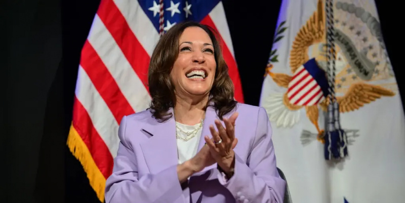 Kamala Harris purtând un costum mov și zâmbind