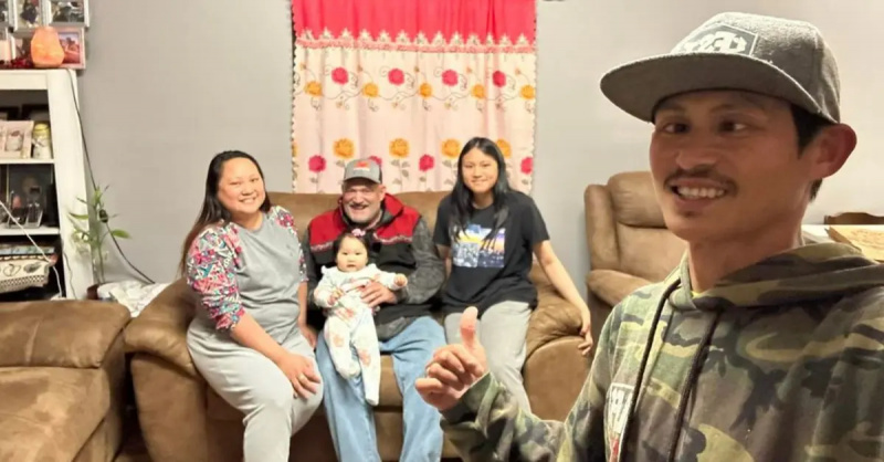 Oj(站在右侧)与他的妻子 Keith 上尉自拍,后者抱着 Oj's youngest daughter, and oldest daughter all seated on the couch.