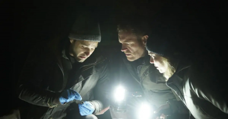 Phil Torres, Heather Amaro i Josh Gates badają coś przy włączonych nocą latarkach'Expedition X'