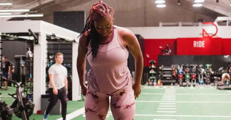 Ashley Michelle von 90 Day Fiance in einem rosa Tanktop und Leggings in einem Fitnessstudio