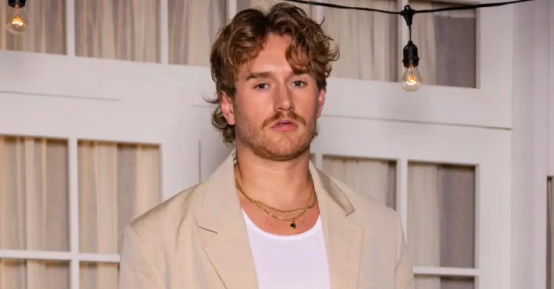 West Wilson bär en överdimensionerad beige kostym över ett klassiskt vitt linne med lager av guldhalsband för'Summer House' Season 8 reunion.