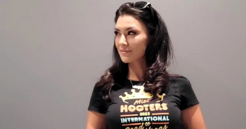 Averey Tressler desvia o olhar da câmera enquanto veste uma camisa 2023 Miss Hooters International.