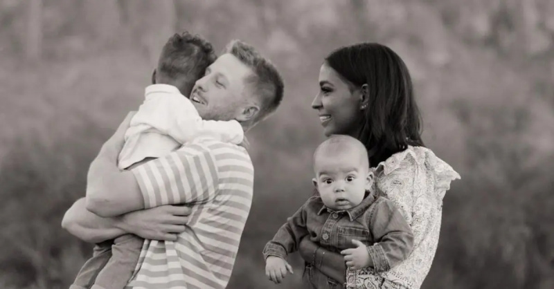 Clayton Wessel își ține în brațe fiul cel mare, în timp ce Layla Taylor se uită în timp ce ține în brațe copilul lor cel mai mic pentru o fotografie de familie.