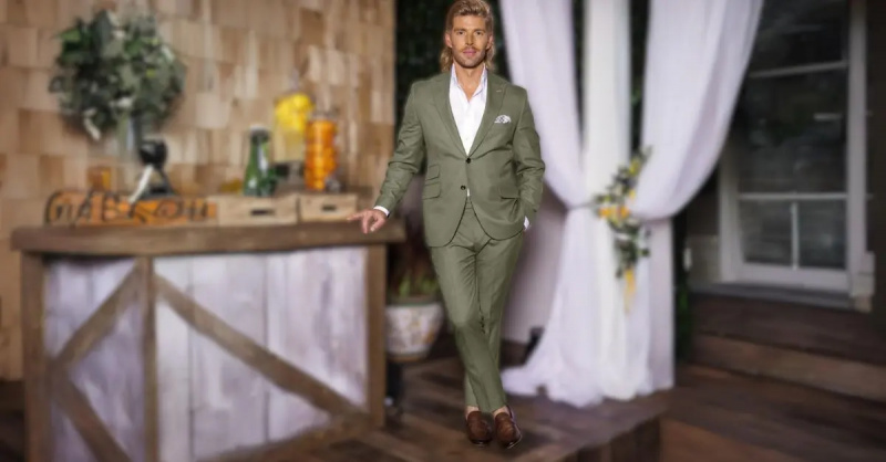 Kyle Cooke poserar på'Summer House' Season 8 reunion set with one hand in his pocket leaning on a bar