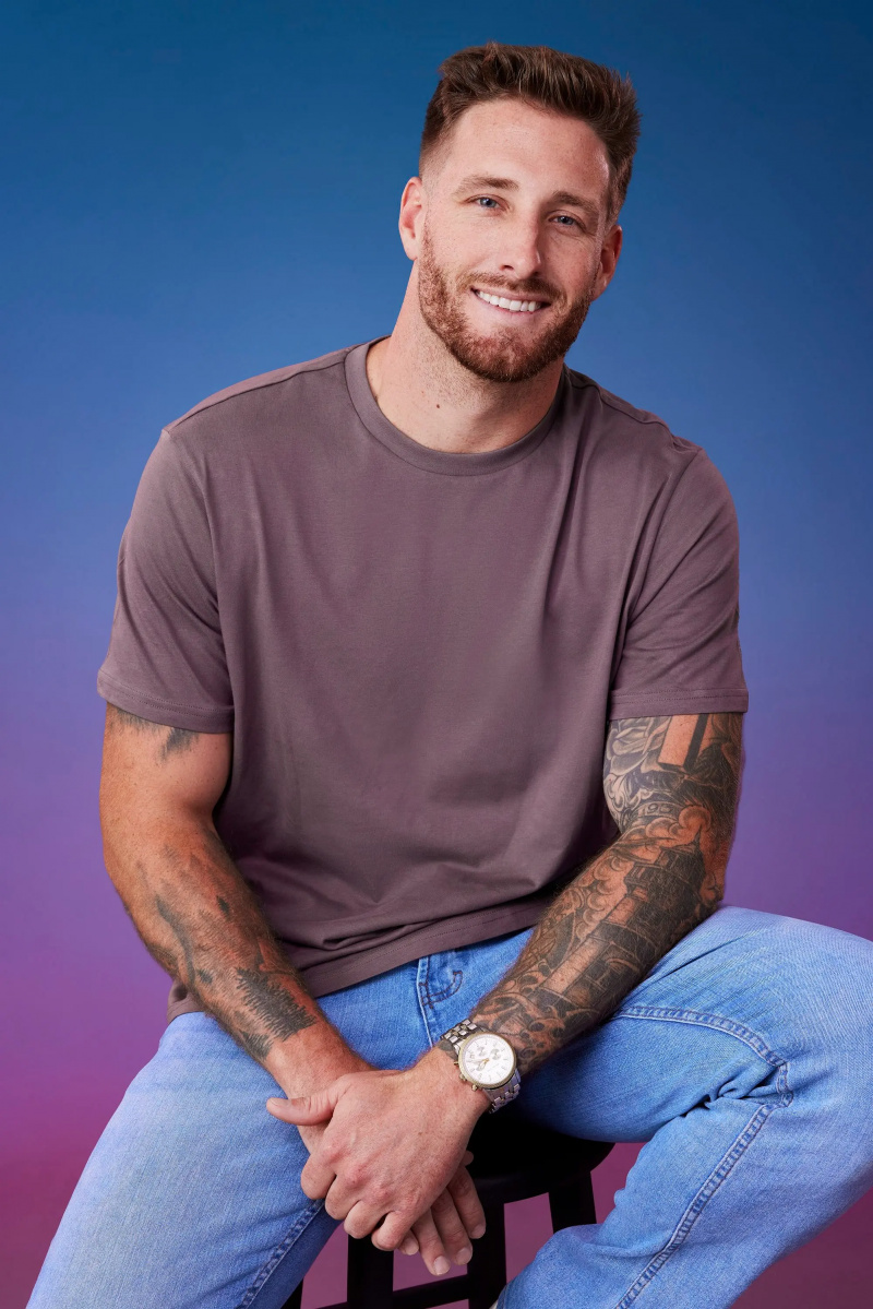 Sam M. 在他的官方蓝紫色渐变背景前摆姿势'The Bachelorette' Season 21 portrait.