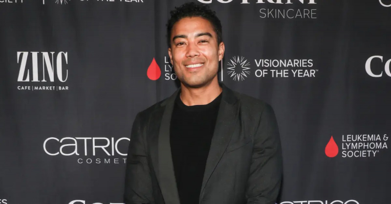 Jason Caperna se usmívá a pózuje v elegantním černém obleku na červeném koberci v Sparkle's Drag Spectacular on April 27, 2024 in North Hollywood.