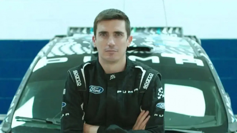 Craig Breen sentado no capô de seu carro de corrida