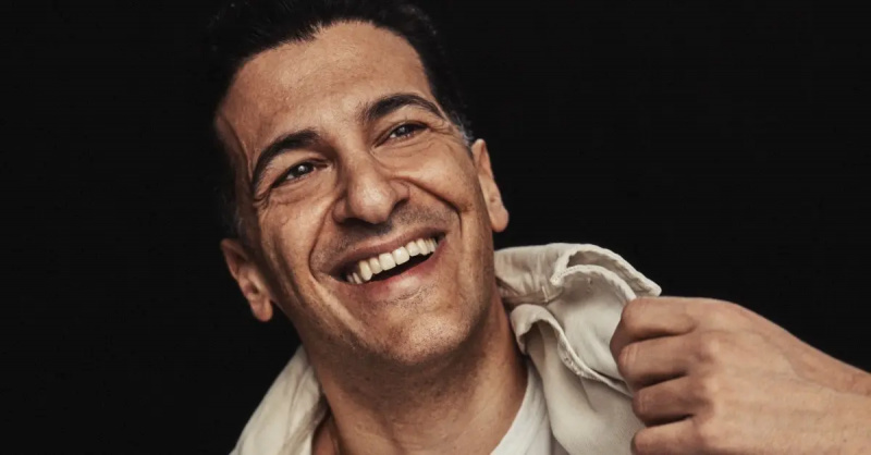 Simon Kassianides ler i vit skjorta och vit kavaj