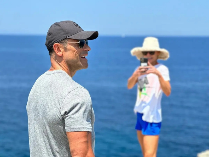 Mark Consuelos poserer og smiler på stranden mens Kelly Ripa fotograferer ham