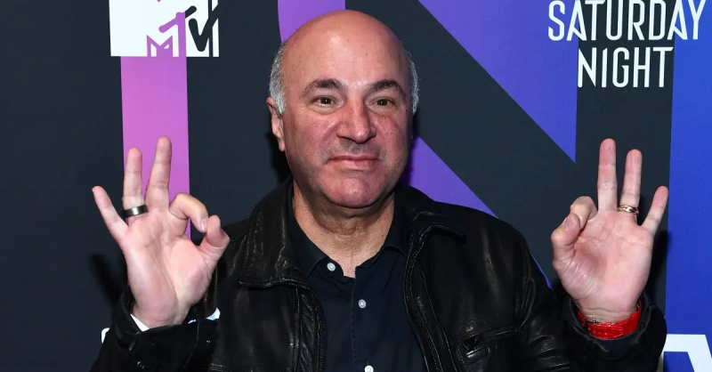 Кевін О'Leary posing in front of a pink, purple, and blue background at AT&T TV Super Saturday Night at Meridian at Island Gardens.