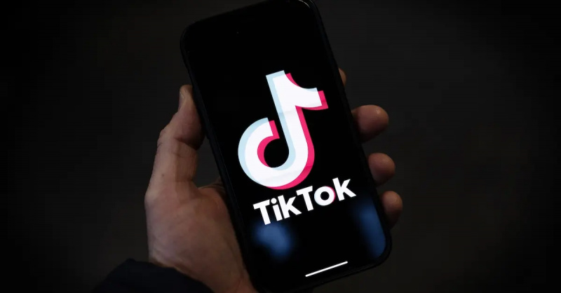 En person som håller en smartphone med TikTok's logo displayed