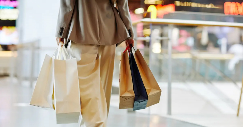 une femme marche avec des sacs à provisions dans un centre commercial, vue de derrière