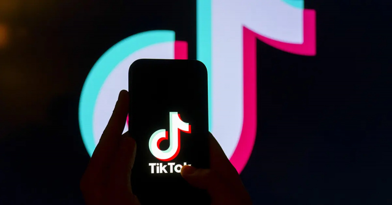 TikTok-logo puhelimessa, jonka takana on TikTok-logo.